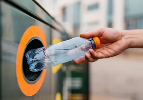 Hand recycling plastic bottle in bin.